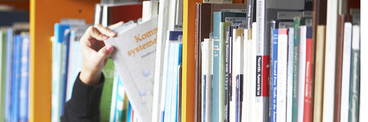 Person tager en bog fra bogreol